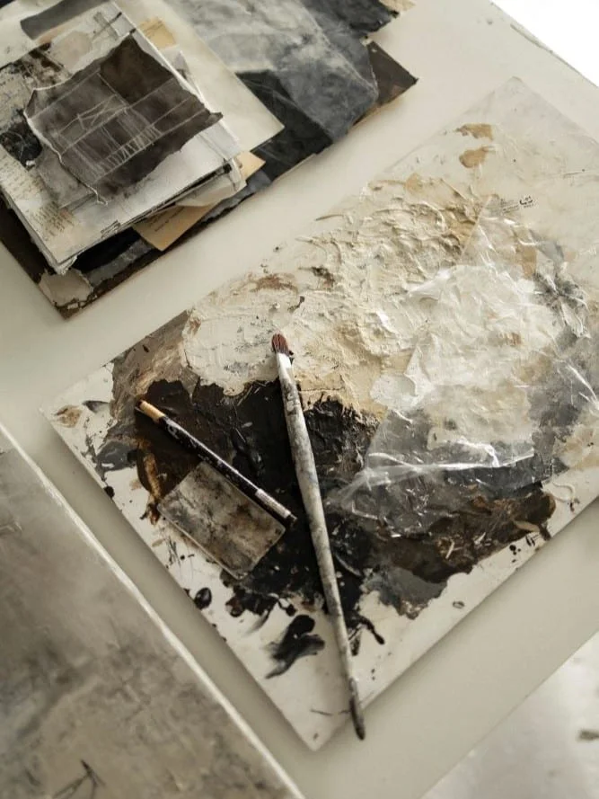 table in studio of the artist jolanda wassenaar, with paint, pencil and carcoal in white, beige and black colours